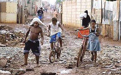  Crianças transitam por rua com lixo e lama em favela do Rio de Janeiro 